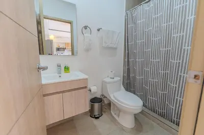 a bathroom with a toilet and a sink and a mirror at Margo 306- Luxe, Elegant & Cozy Condo- City Center in San Salvador