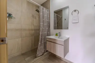 a bathroom with a shower and a sink and a mirror at Margo 306- Luxe, Elegant & Cozy Condo- City Center in San Salvador
