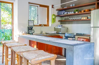 a kitchen with a counter with a row of stools at SantiChanti Walk to Sunzal Beach in Tamanique
