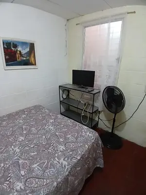 a bedroom with a bed and a desk with a laptop at Santa Tecla Acogedora Guest House in Nueva San Salvador