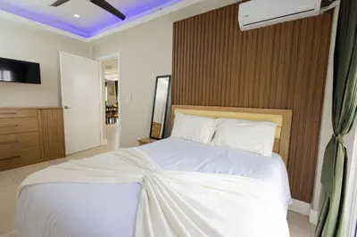 a bedroom with a white bed with a wooden headboard at Family Friendly Guanaco House El Salvador AC, Wi-Fi, Hot Water, & Enjoy Your Stay in Santa Ana