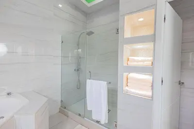 a white bathroom with a shower and a sink at Family Friendly Guanaco House El Salvador AC, Wi-Fi, Hot Water, & Enjoy Your Stay in Santa Ana
