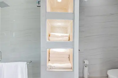 a bathroom with a shelf with towels and towels at Family Friendly Guanaco House El Salvador AC, Wi-Fi, Hot Water, & Enjoy Your Stay in Santa Ana