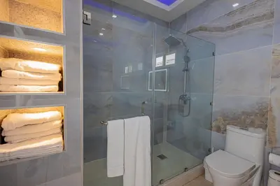 a bathroom with a shower and a toilet and towels at Family Friendly Guanaco House El Salvador AC, Wi-Fi, Hot Water, & Enjoy Your Stay in Santa Ana