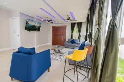 a living room with blue and yellow chairs at Family Friendly Guanaco House El Salvador AC, Wi-Fi, Hot Water, & Enjoy Your Stay in Santa Ana