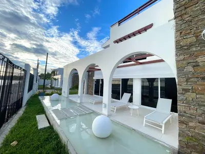 a white patio with white chairs and a stone building at Mariposa Reina B in El Jagüey