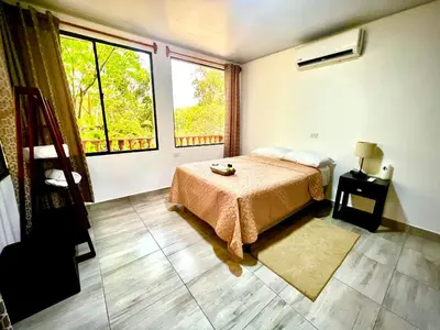 a bedroom with a bed and a large window at Mayara Hostal in El Zonte