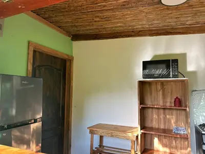 a room with a wooden shelf with a microwave on it at Mayara Hostal in El Zonte