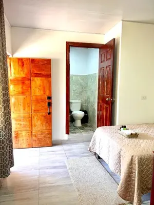 a bedroom with a bed and a bathroom with a toilet at Mayara Hostal in El Zonte