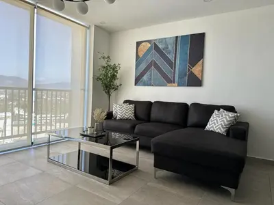 a living room with a black couch and a glass table at Modern Apartment in Downtown. A/C+ Wifi! in San Salvador