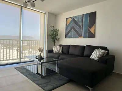 a living room with a black couch and a glass table at Modern Apartment in Downtown. A/C+ Wifi! in San Salvador