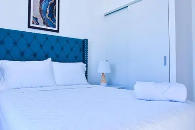 a bedroom with a white bed with a blue headboard at Modern Apartment in Downtown. A/C+ Wifi! in San Salvador