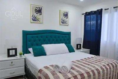 a bedroom with a large bed with a green headboard at The Downtown Apartment - 3 A/C bedroom + WiFi in San Salvador