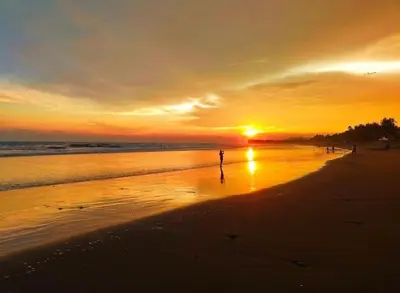 a person standing on a beach at sunset at Barú in La Libertad