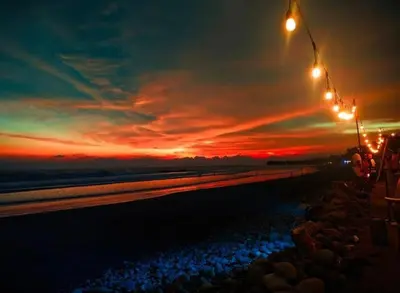 a sunset on the beach with lights and rocks at Barú in La Libertad