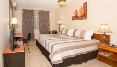 a hotel room with a bed and a television at Hotel Tropico Inn in San Miguel