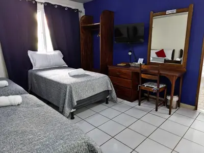 a bedroom with two beds and a desk with a mirror at Hotel Sueños in San Salvador