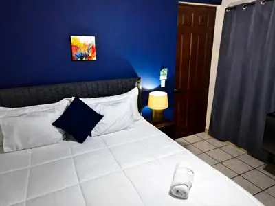 a bedroom with a large white bed with a blue wall at Hotel Sueños in San Salvador