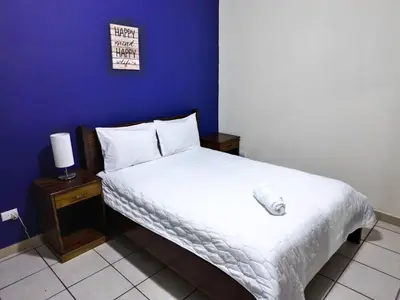 a bedroom with a white bed with a blue wall at Hotel Sueños in San Salvador