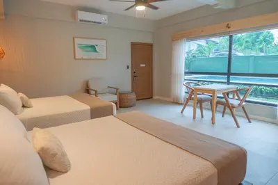 a bedroom with two beds and a table and a window at Mirasurf Hotel & Waves in El Sunzal