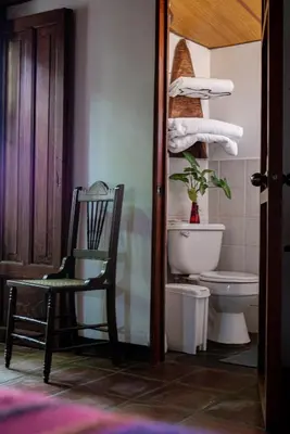 a bathroom with a chair and a toilet and towels at Hotel Anáhuac in Juayúa
