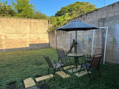 a table and chairs under an umbrella in a yard at Apartamento entero Rebeca house in Santa Ana