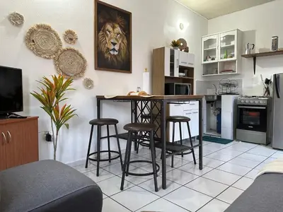 a living room with a kitchen with a table and stools at Apartamento entero Rebeca house in Santa Ana