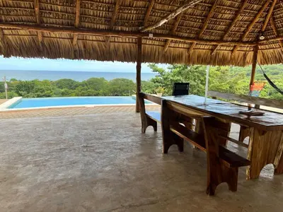 a desk in a straw hut with a laptop on it at Rancho Agua Fria in Jucuarán