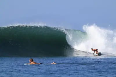 two people riding a wave on surfboards in the ocean at Rancho Agua Fria casa in Usulután