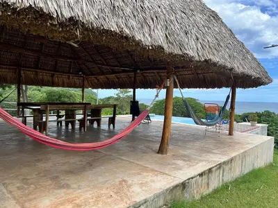 a hammock and a table and a straw umbrella at Rancho Agua Fria casa in Usulután