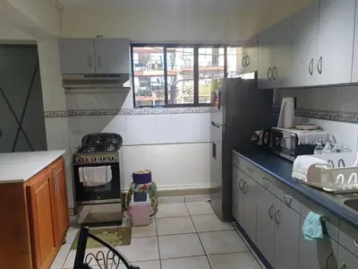 a kitchen with white cabinets and a black refrigerator at Isabela´s Quality Accommodation in San Salvador