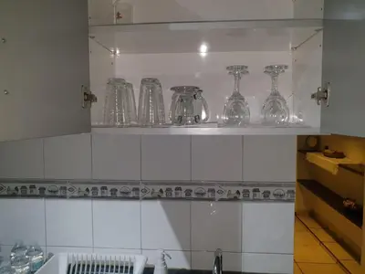 a kitchen with glasses on a shelf above a sink at Isabela´s Quality Accommodation in San Salvador