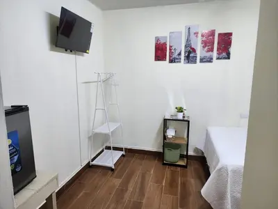a white room with a bed and a tv and a wooden floor at GYWEL 1214 in San Salvador