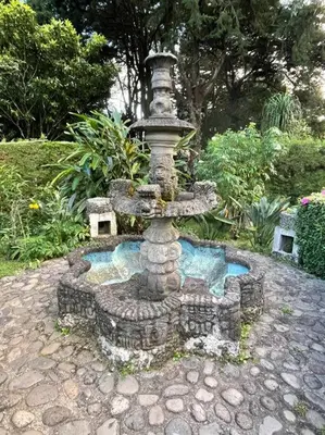 a fountain in the middle of a garden at Casa Villas Suizas I cerca de Laberinto de Albania in Apaneca