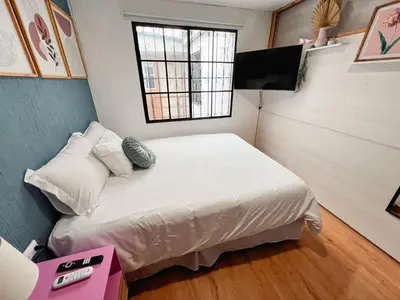 a small bedroom with a bed and a television at Casa 46 - Escalon in San Salvador