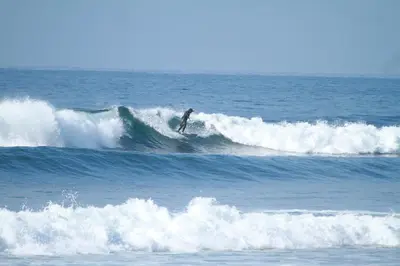 a person riding a wave on a surfboard in the ocean at Shalpabay - Rooms in Taquillo