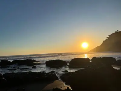 a sunset on the beach with rocks in the water at Shalpabay - Rooms in Taquillo