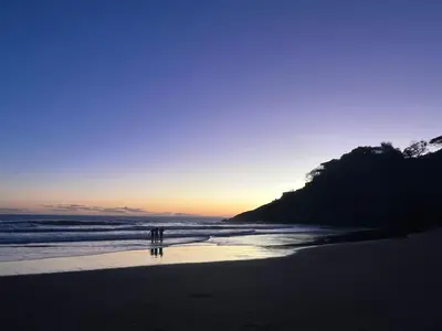 two people walking on the beach at sunset at Shalpabay House in Taquillo
