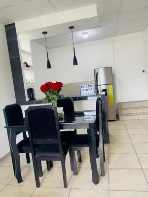 a dining room table with chairs and a vase of flowers on it at Stay Loft Mejicanos A 10 min del Centro Histórico in Mexicanos