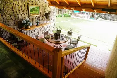 a balcony with a table and chairs and a stone wall at Cabaña en las Montañas de El Trifinio in Metapán