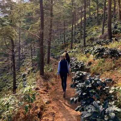 a woman walking down a trail in the woods at Cabaña en las Montañas de El Trifinio in Metapán