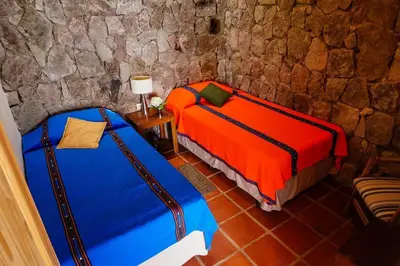 two beds in a room with a stone wall at Cabaña en las Montañas de El Trifinio in Metapán