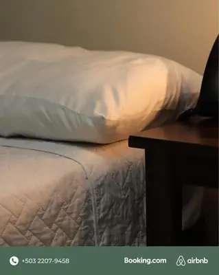 a white pillow sitting on a bed next to a table at Lorenzo Hotel in San Salvador