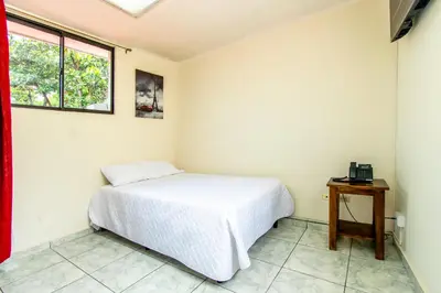 a bedroom with a white bed and a table at Lorenzo Hotel in San Salvador