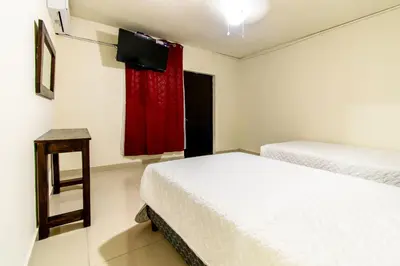 a bedroom with two beds and a window with a red curtain at Lorenzo Hotel in San Salvador