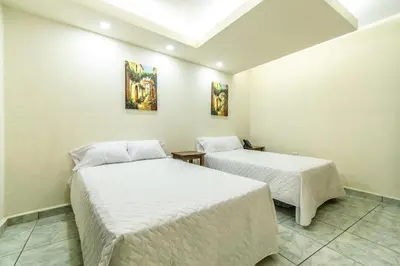 two beds in a room with white walls at Lorenzo Hotel in San Salvador