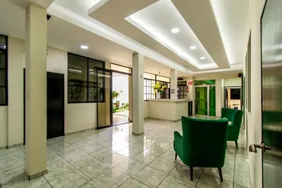 a lobby with green chairs and a table at Lorenzo Hotel in San Salvador