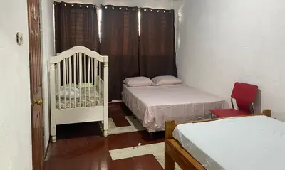 a small bedroom with two beds and a crib at Casa Juayúa in Juayúa