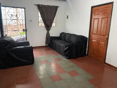 a living room with a black leather couch and a door at Casa Juayúa in Juayúa