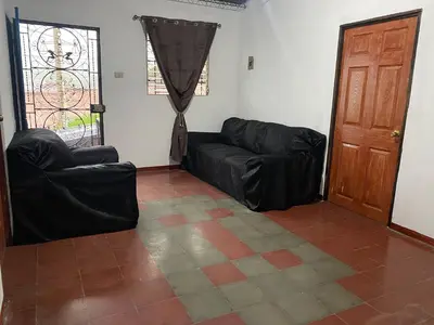 a living room with a black leather couch and a door at Casa Juayúa in Juayúa